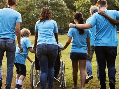Image of a person in a wheelchair and several other ambulatory people in blue shirts.