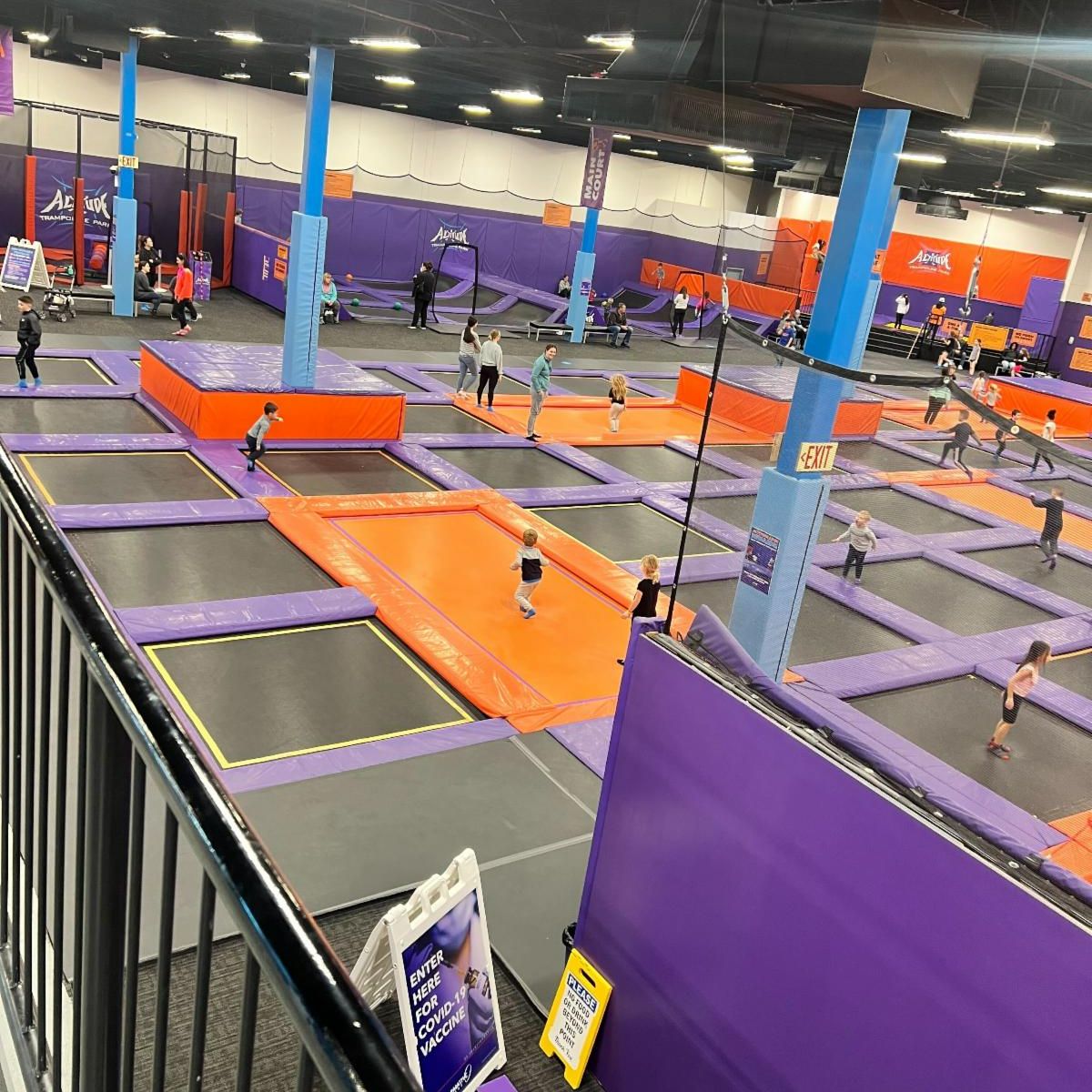 An indoor trampoline park. Kids are having fun and exploring different trampolines on the floor.