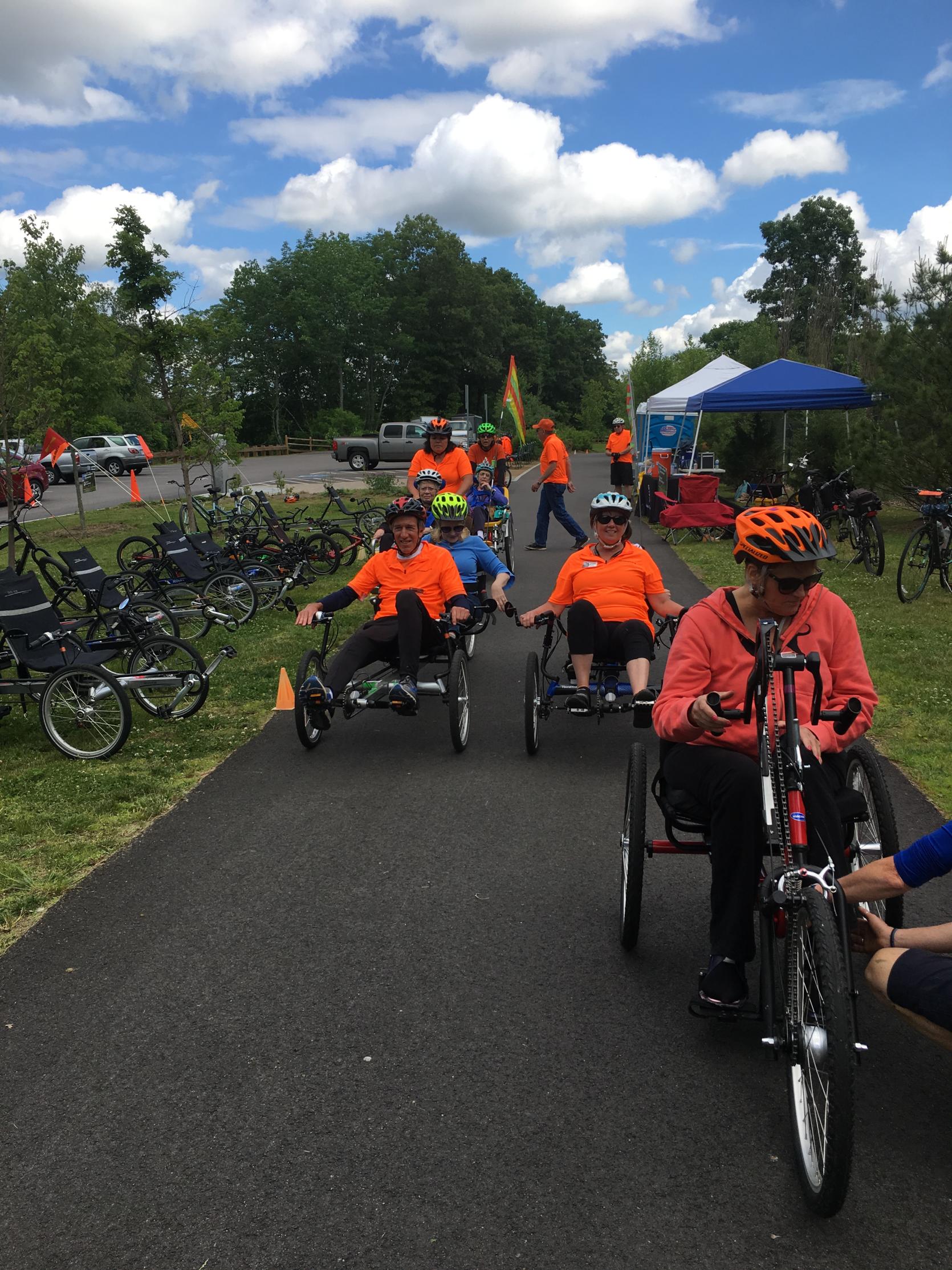 Cyclists on a bike path riding recumbent tandems, handcycles, and other adaptive cycles.