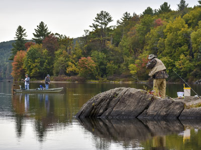 Two men standing up fishing from their boat