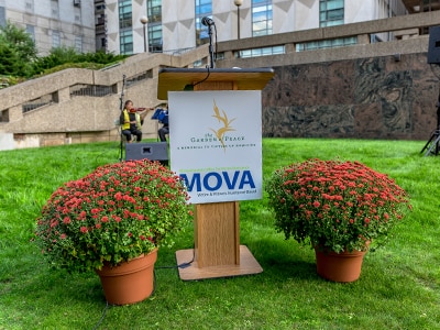 Podium with Garden of Peace and MOVA logos and flowers