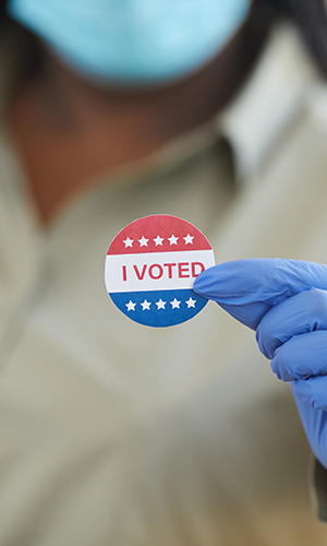 An I voted sticker in a gloved hand