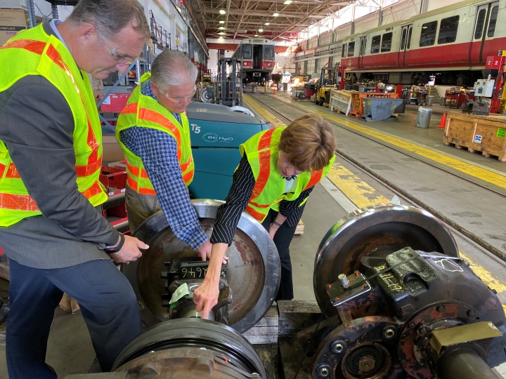 Auditor Bump, with employees of the MBTA, inspecting bus parts in an MBTA garage. 