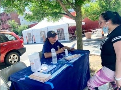 A vaccine equity worker at a table helping residents register for vaccine appointments.