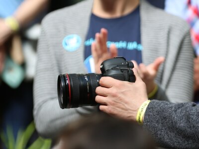 Someone holding a camera taking pictures of people clapping