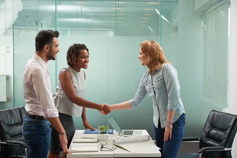 Image of new hire shaking hands with employers at interview 