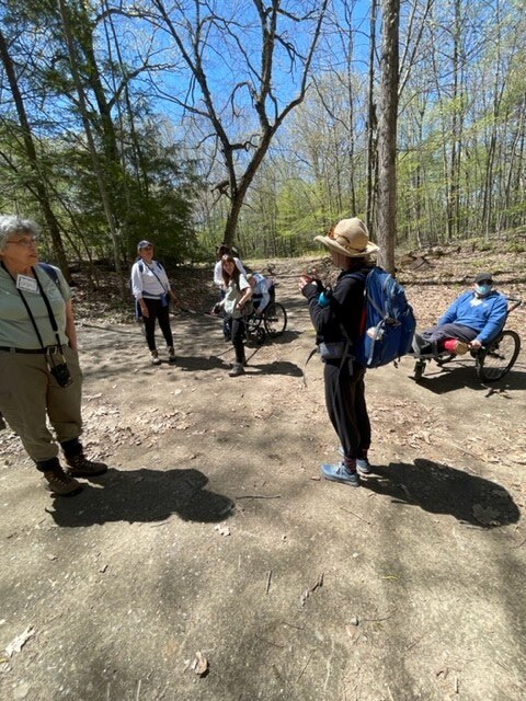 A group of hikers gather in a circle at the edge of the woods before a hike