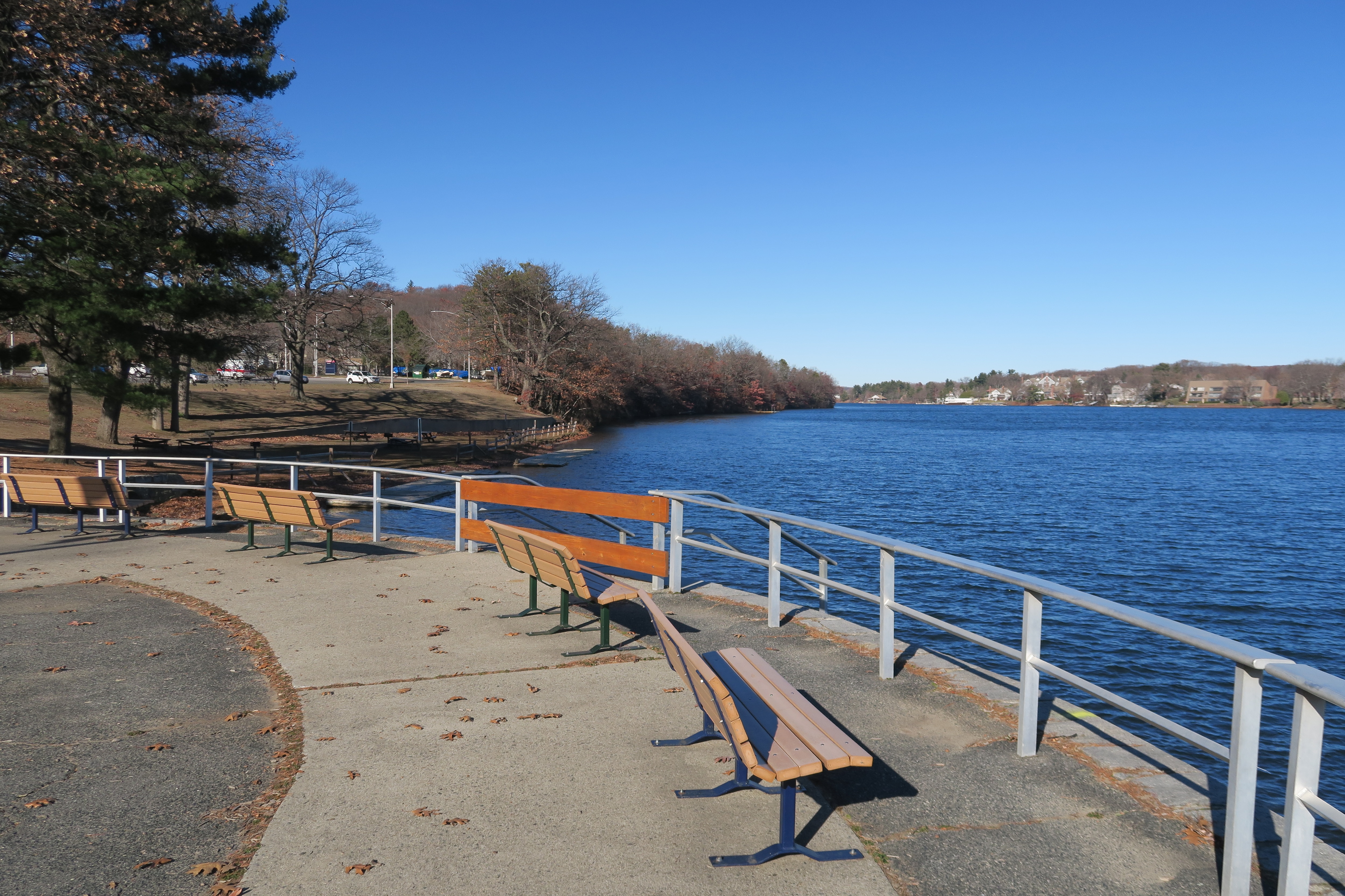 A curved promenade with benches and a railing overlooks the water.