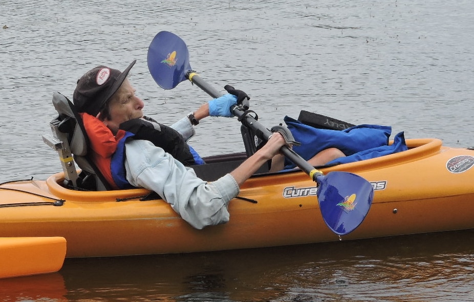 A paddler using a paddle with hand grips. The paddler also has pillows and foam between their legs and the kayak hull.