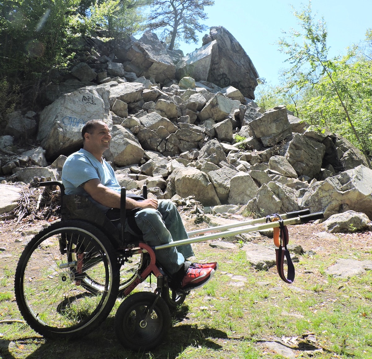 A hiker sits in a Terra Trek wheelchair with rickshaw poles on the front.