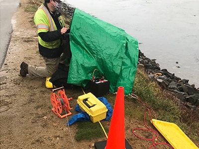 A person conducting a geophysical investigation along the bank of the Cape Cod Canal.
