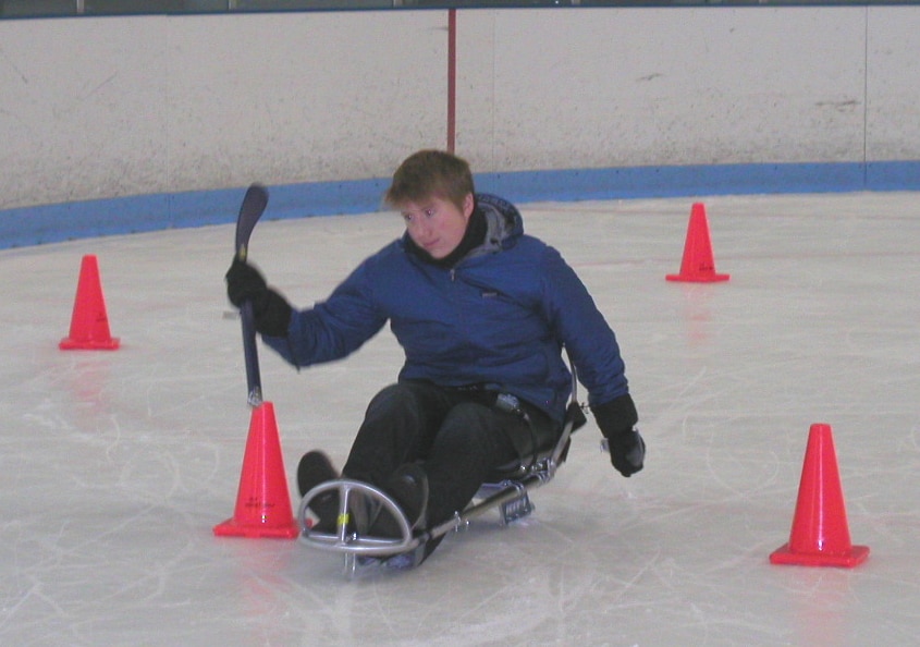 A sled skater skates close by some cones.
