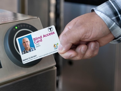 Hand holding Blind Access Card and tapping at fare gate