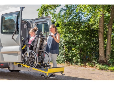 An individual in a wheelchair using assitive technology to get into a van