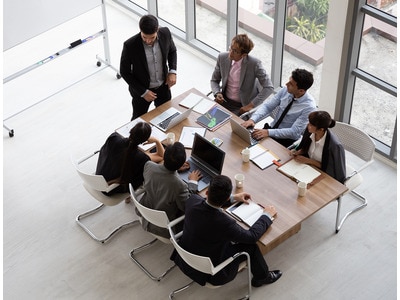 An image taken from above of a group of employees in business wear working together around a table 