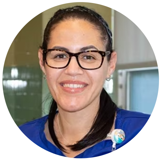 Brenda Baez is a registered nurse at the  Tewksbury Hospital. She has a friendly smile. She wears glasses and a blue medical uniform at work.
