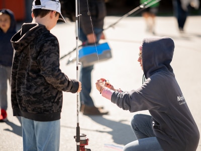 An angling instructor helping a young angler learn to fish.