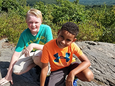 Two boys sitting on a rock.