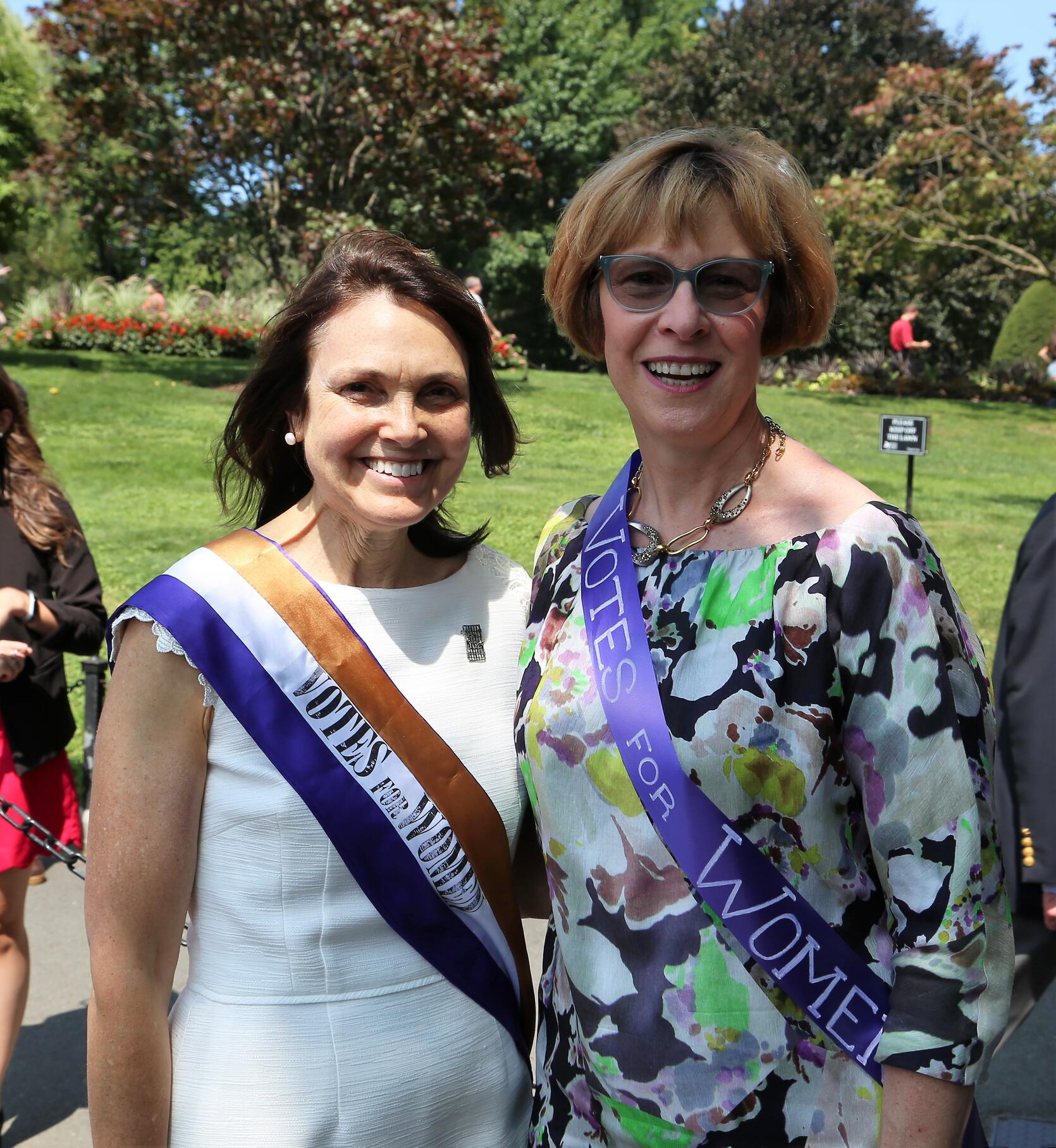 Auditor Bump with Fredie Kay, President of the Women's Suffrage Celebration, wearing suffragette sashes.