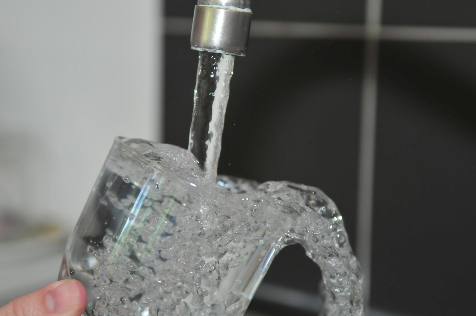 A glass being filled with water by a faucet.