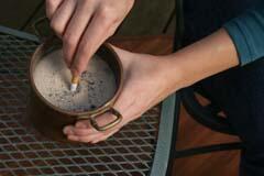 Putting old cigarette in can with sand