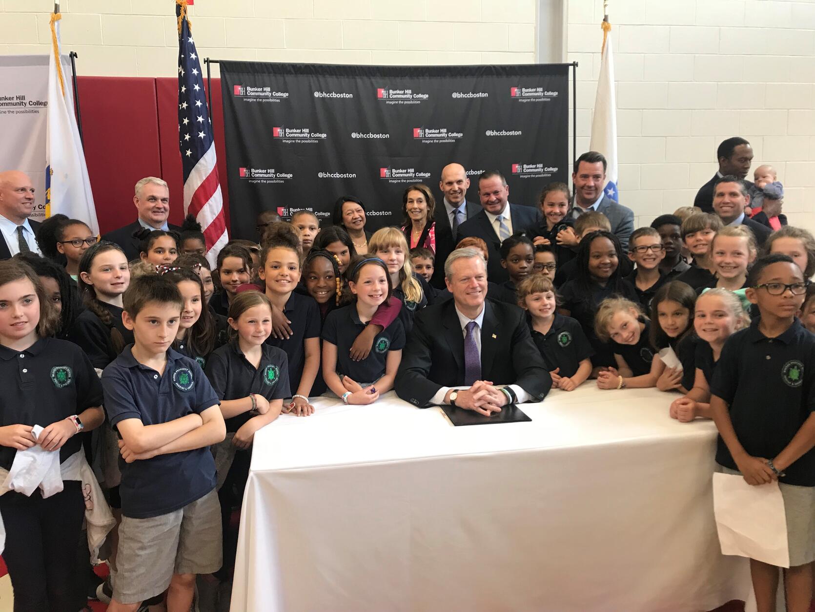 • Gov. Charlie Baker is surrounded by third graders from Warren Prescott School in Charlestown as he announces $20 million in life science funding for 23 Massachusetts companies. Baker was also joined at Bunker Hill Community College by state officials and representatives of life science companies.