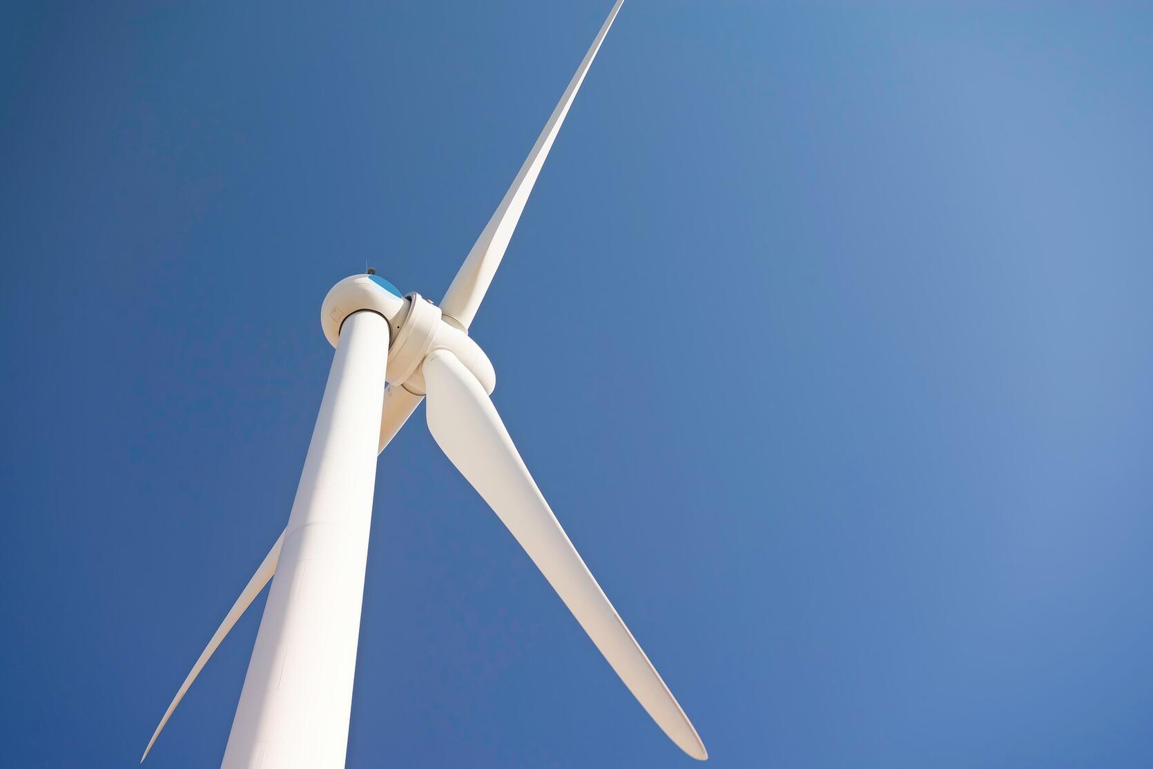 White wind turbine at rest in front of a clear blue sky.