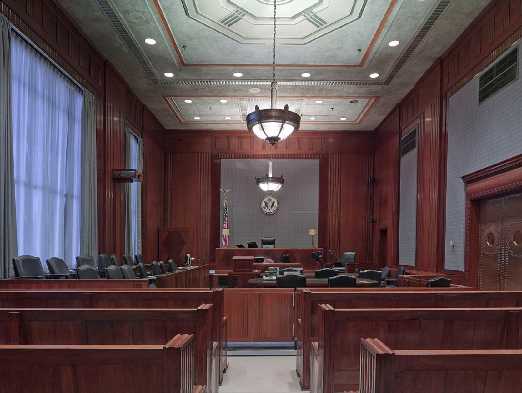 The inside of a courtroom, with dark benches. 