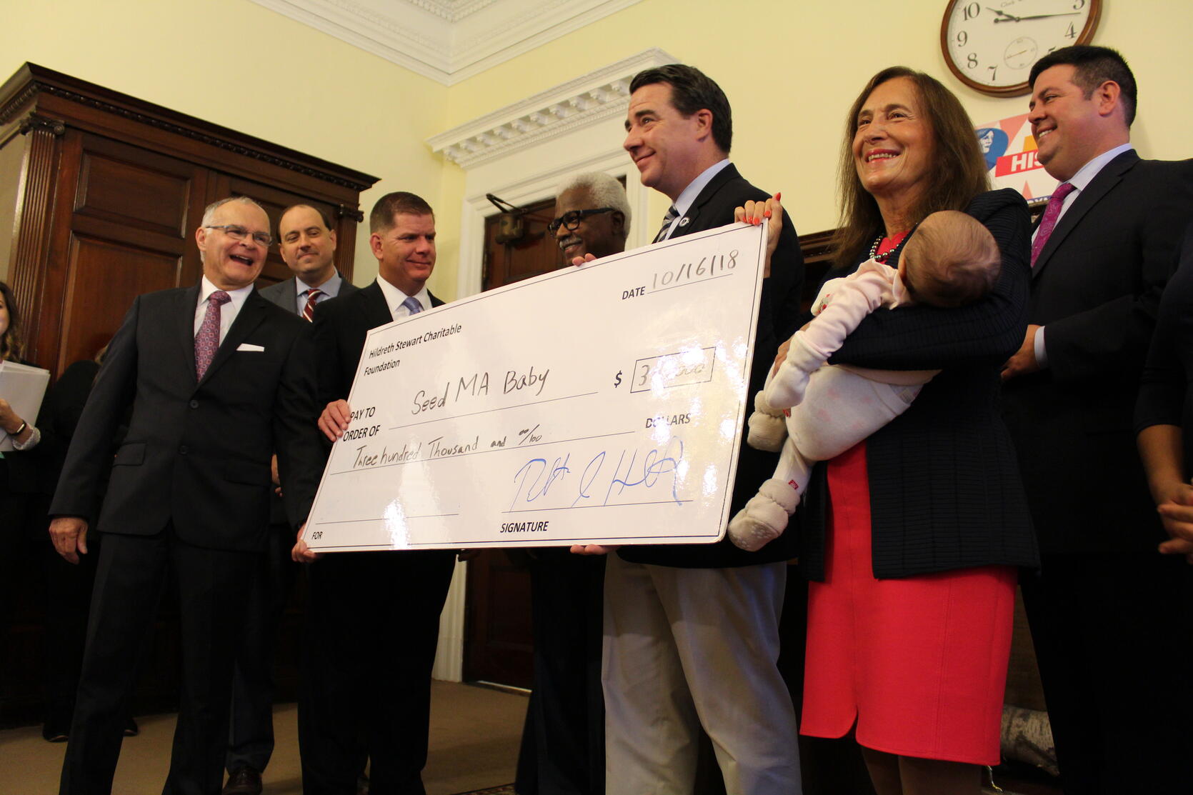 Photo of Treasurer Goldberg holding a baby in front a check for SeedMA Baby, standing across from Boston Mayor Marty Walsh