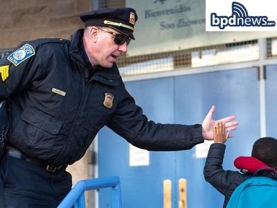 Police officer and elementary kid gving each other a high five