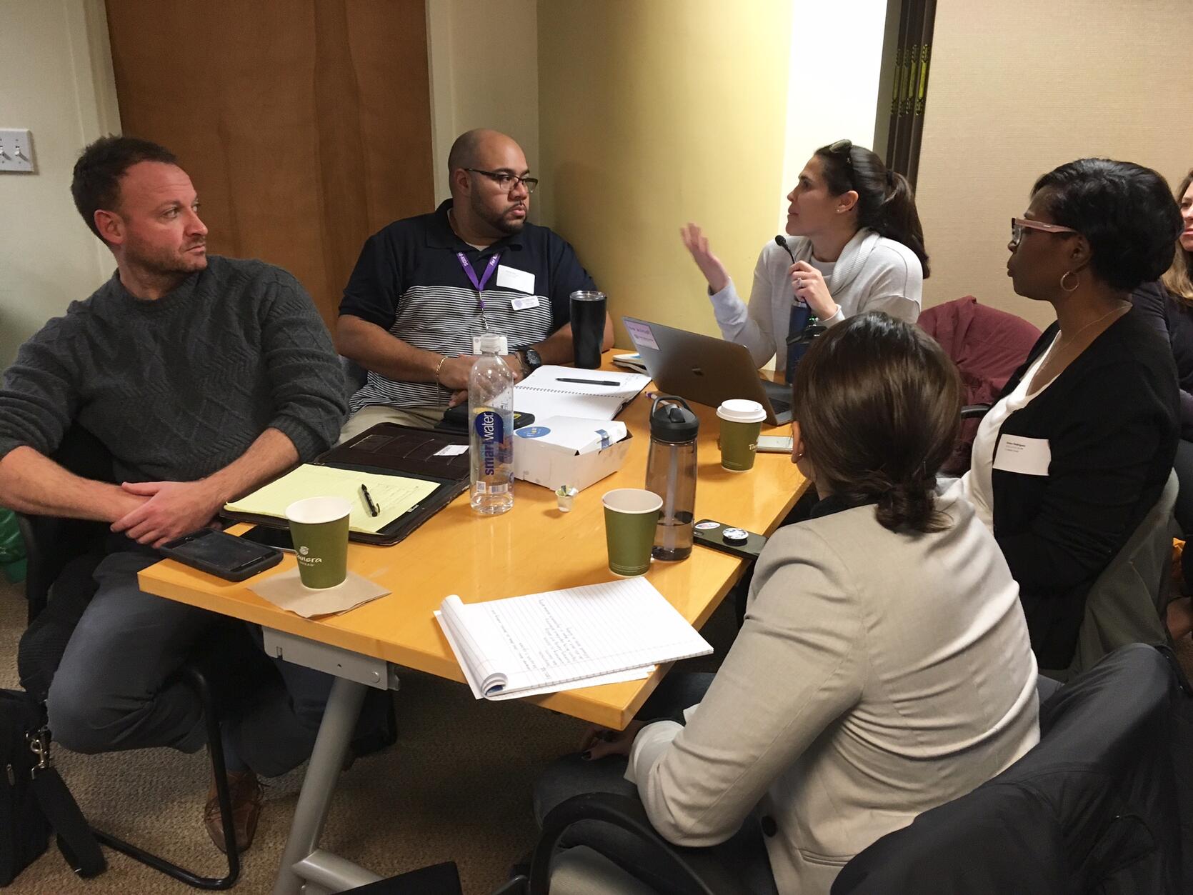 This is a photo of a group of educators sitting around a table and having a discussion.