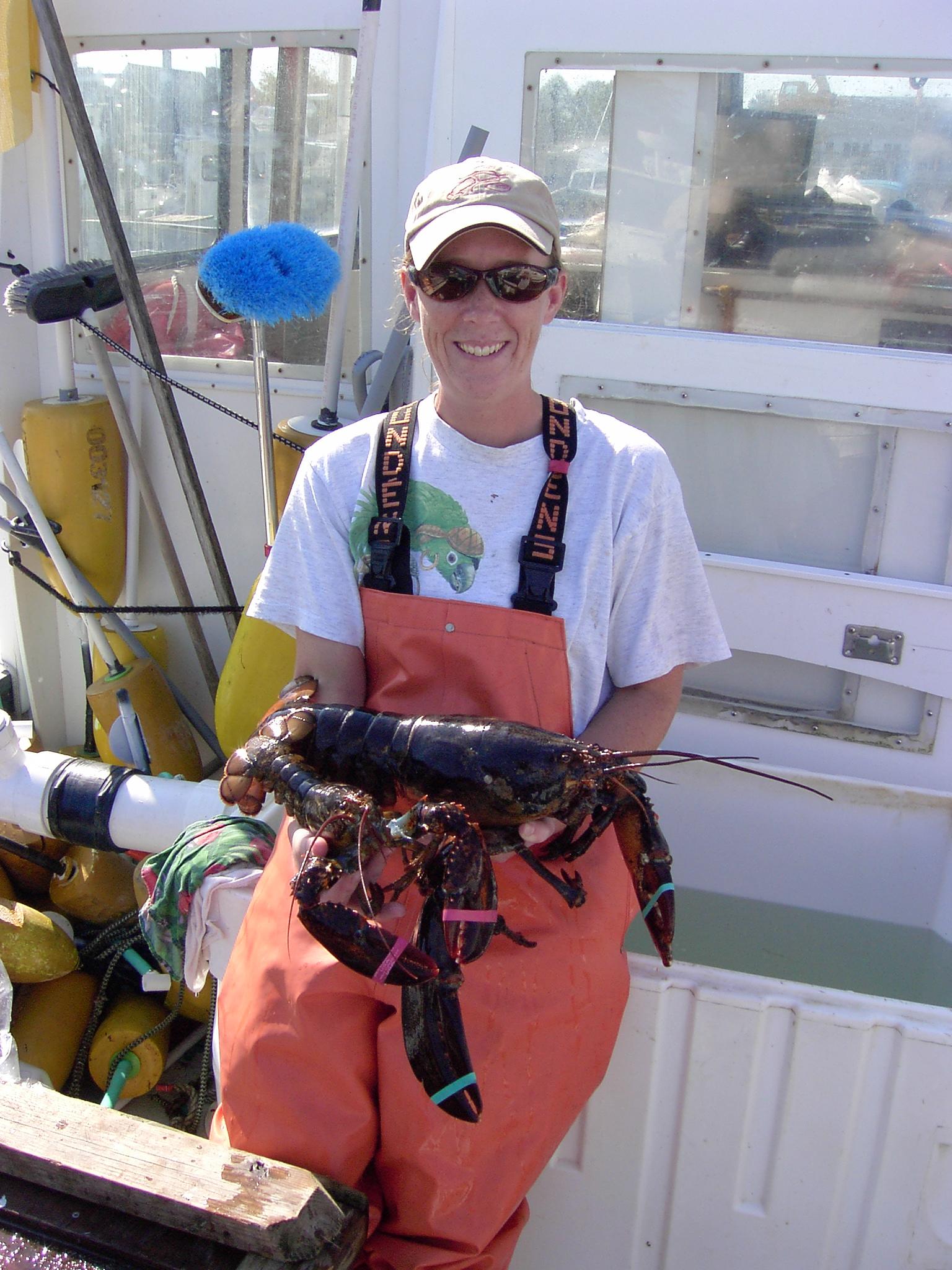 Invertebrate Fisheries Project Leader, Tracy Pugh at end of a sampling day aboard the vessel F/V Victoria Rose. The larger lobster is a female, the smaller one is a male.  