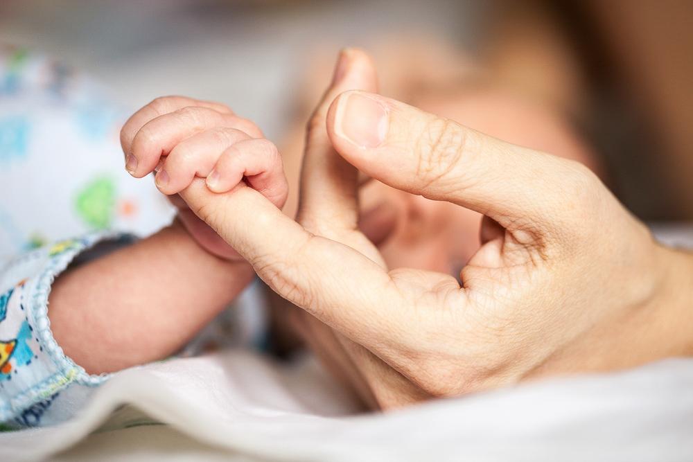 Newborn holding mother's hand