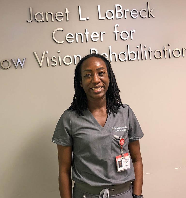 Dr. Stephanie Aigbe standing in front of Janet L. LaBreck Center for Low Vision Rehabilitation sign