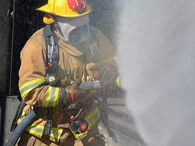 firefighter holding water hose and water spraying