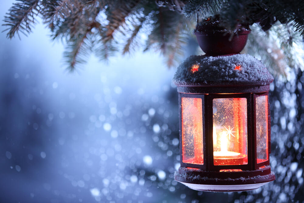 Winter lantern glowing in snow with tree