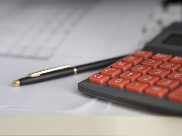 A calculator and pen sitting on top of a spreadsheet