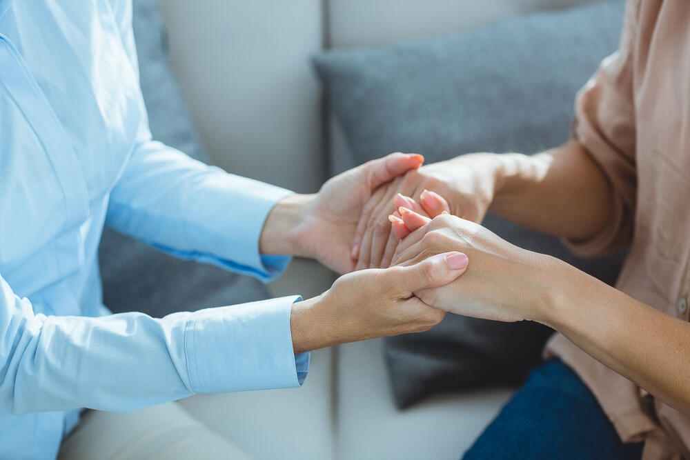 Two individuals facing one another with hands clasped for support