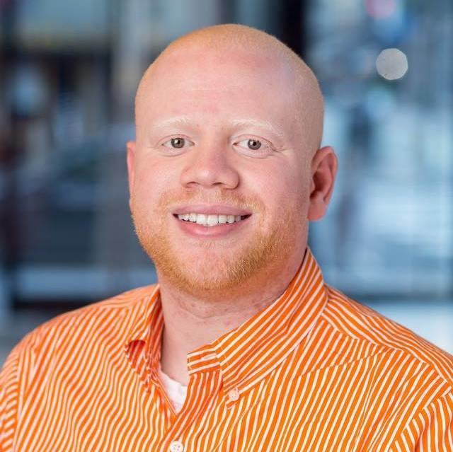 Headshot photo of Phillip Mason smiling in orange work shirt