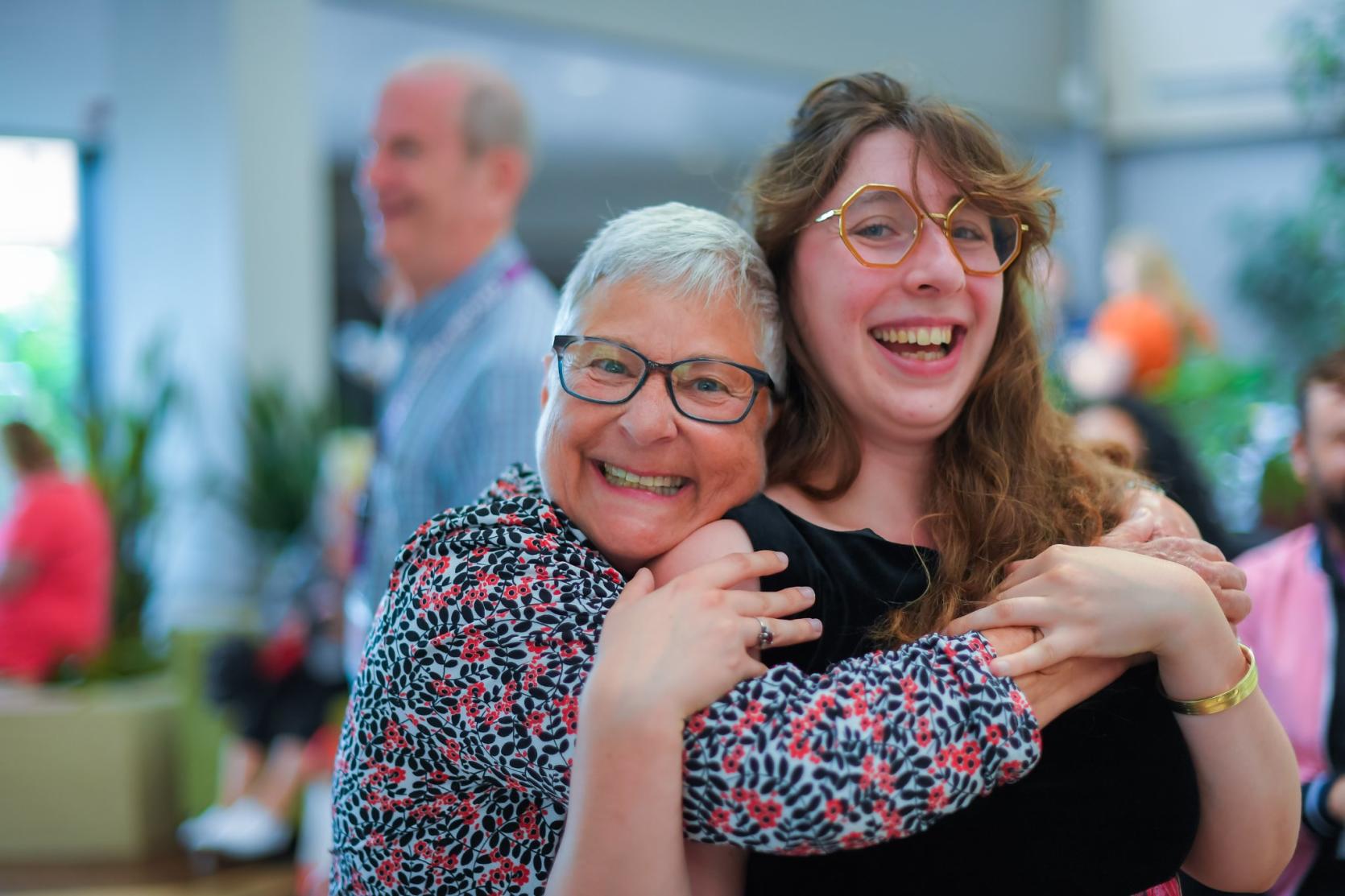 two women embrace and smile at the camera