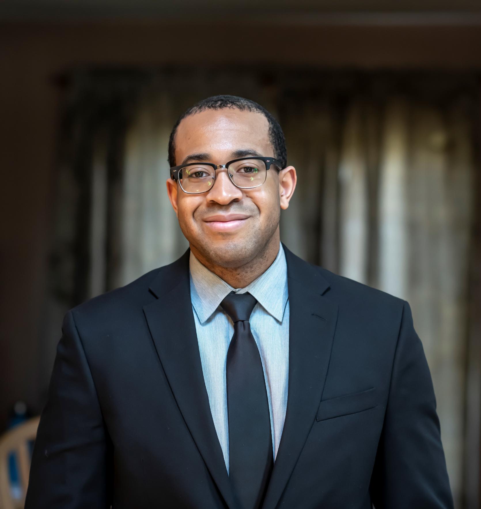 Black man with glasses and dark suit