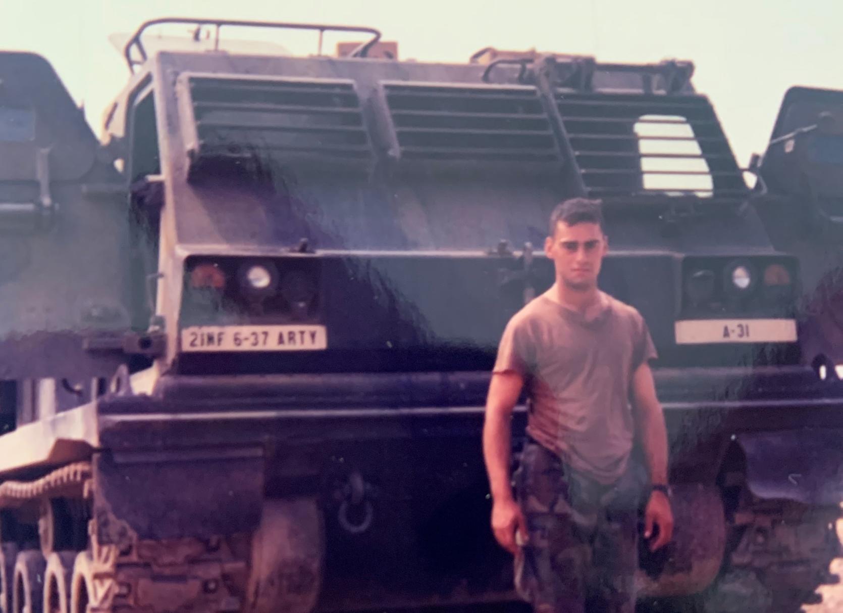 Richard Patchin stands in front of a military vehicle