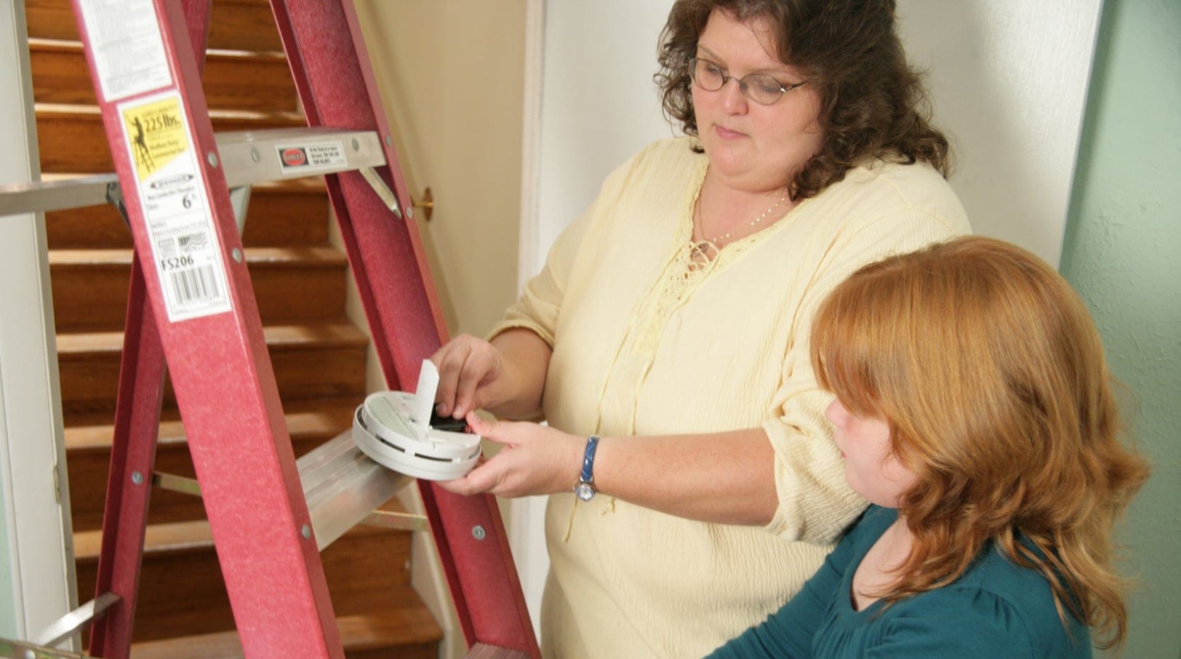  Mother and daughter changing smoke alarm batteries