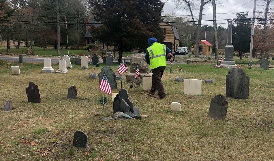 Earth Day clean up crew member weed whacking at the Wapanucket Cemetery