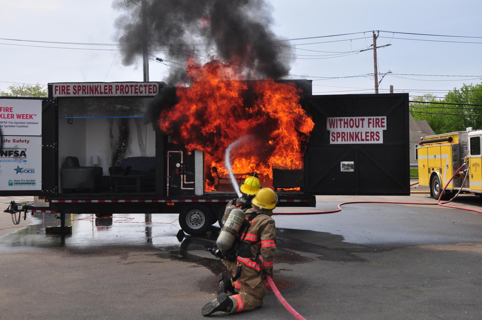 A picture of firefighters using a firehose to extinguish a fire on a trailer