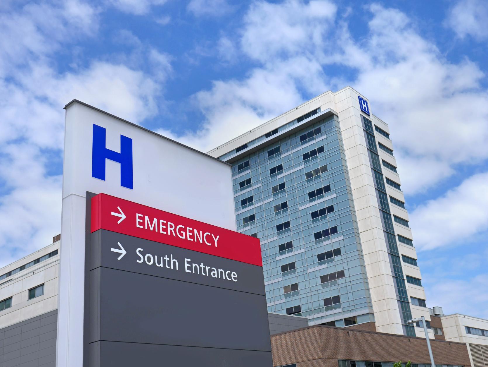 Image of hospital building exterior with signage that points to emergency room.