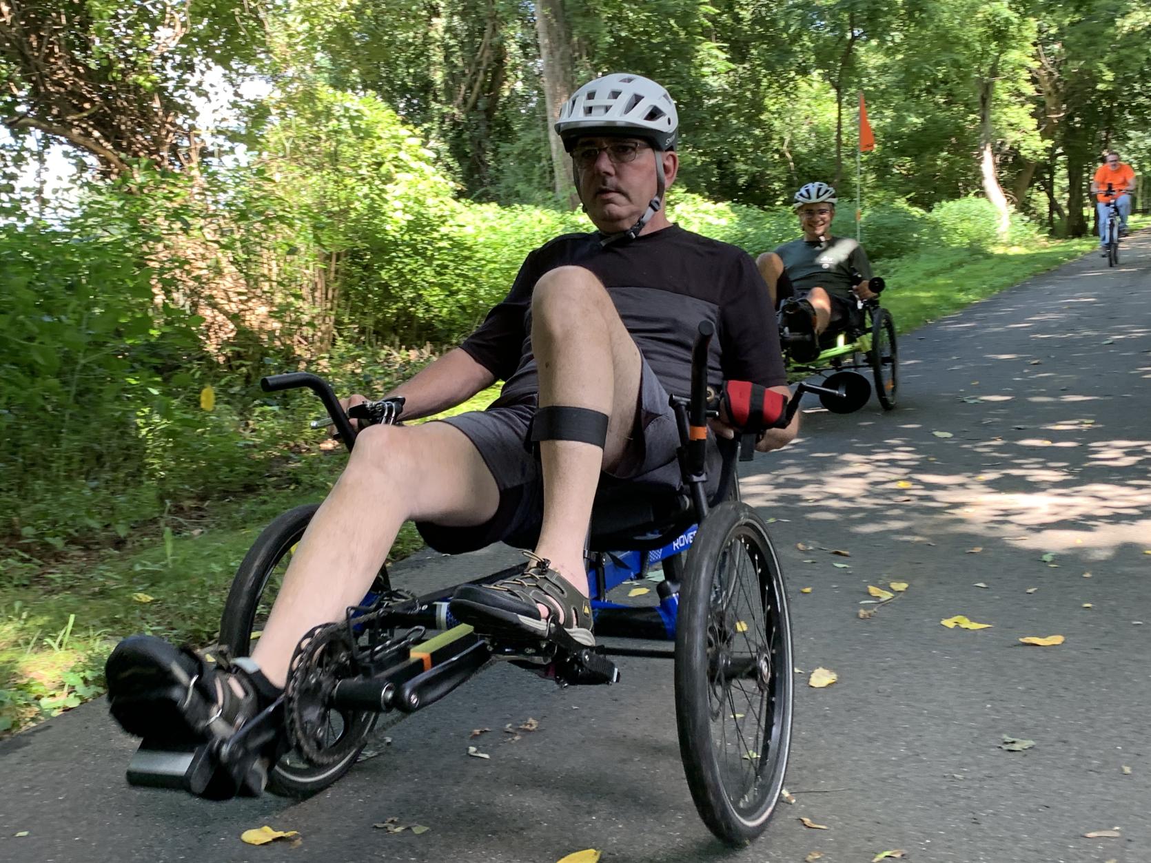 An individual riding an accessible cycle down a paved path