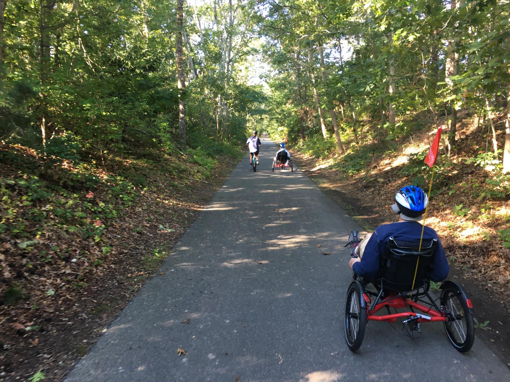 An individual riding an adaptive cycle down a paved path