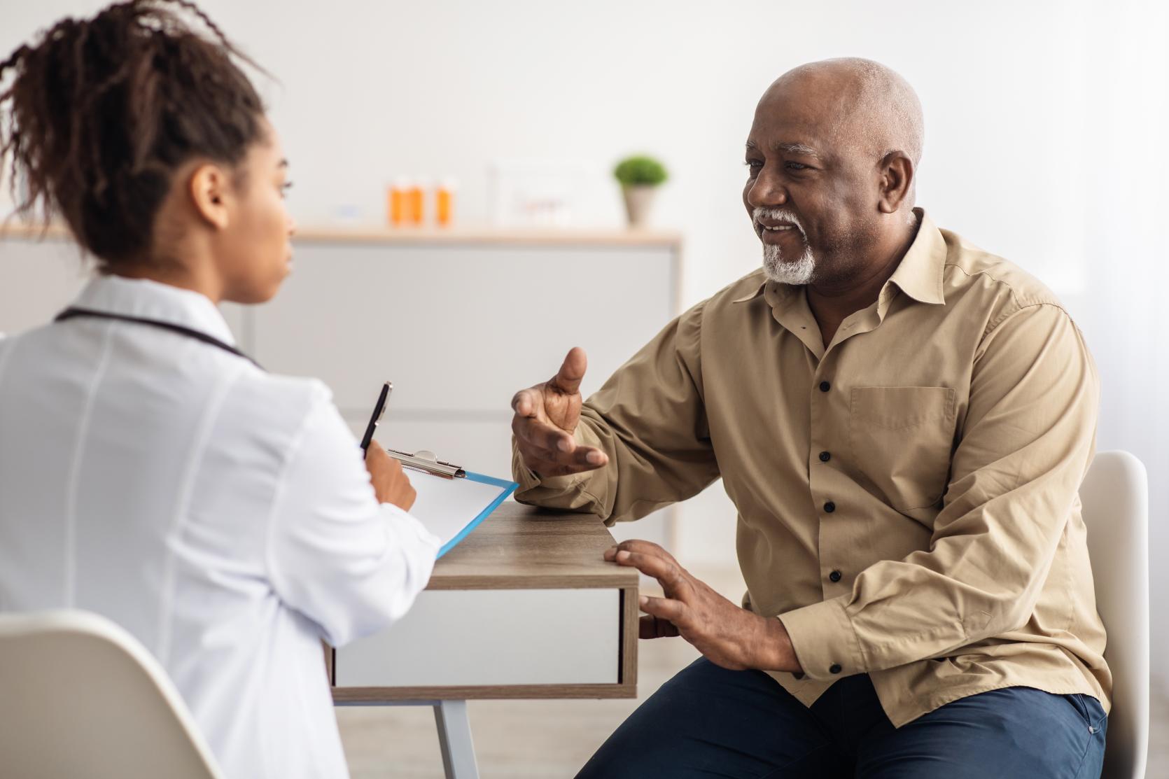 Black female doctor advising an older black male patient.