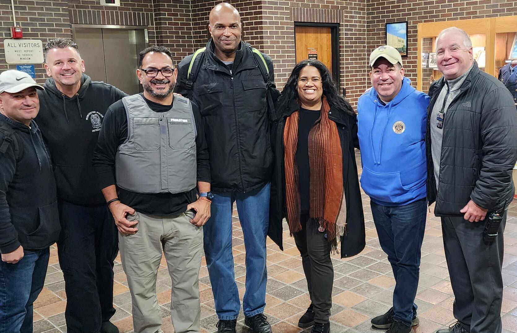 A group of seven people standing in the lobby of a brick building.